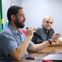 Fala de Eduardo Motta com palestrante ao fundo Fala de Eduardo Motta com palestrante ao fundo