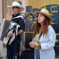 Servidora com chapéu de palha e instrumentista Cowboy da Sanfona em apresentação musical no vernissage da Câmara