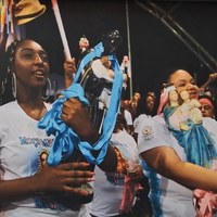 Fotografia de Lázaro Neves com 2 mulheres negras segurando imagens sacras em cortejo religioso tradicional