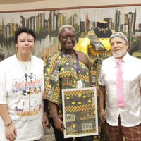 Jovem Aprendiz e servidora da Câmara Municipal de Goiânia junto ao artista Pedro Galvão que segura quadro com estampa de pontos turísticos