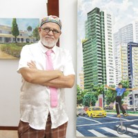 Artista Pedro Galvão de braços cruzados posando ao lado de tela com pintura de prédios modernos e ciclista em Goiânia
