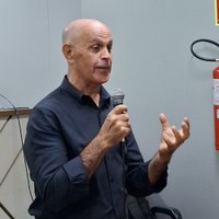 Palestrante João Batista gesticula com mão esquerda e segura microfone durante ministração de curso sobre comunicação assertiva