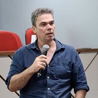 Assessor técnico-legislativo Leonardo Barreto em pé no auditório segurando microfone e gesticulando durante debate sobre emendas parlamentares