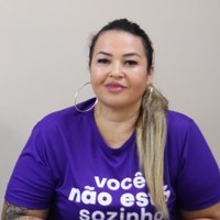 Participante da palestra Juntas Somos Mais Fortes com camiseta roxa em destaque frontal