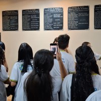 Estudantes em uniforme da rede estadual fotografam placas de legislaturas passadas