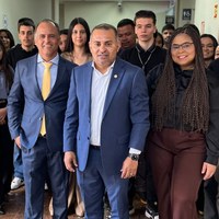 Vereador Ronilson Reis em 1º plano, acompanhado do vereador Willian Veloso à esquerda e grupo de estudantes em corredor interno